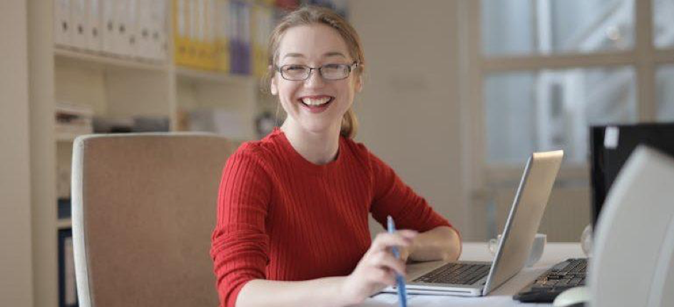 a happy woman with glasses and using her laptop