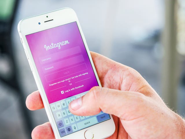 A person holding a phone with the Instagram login page opened on it.